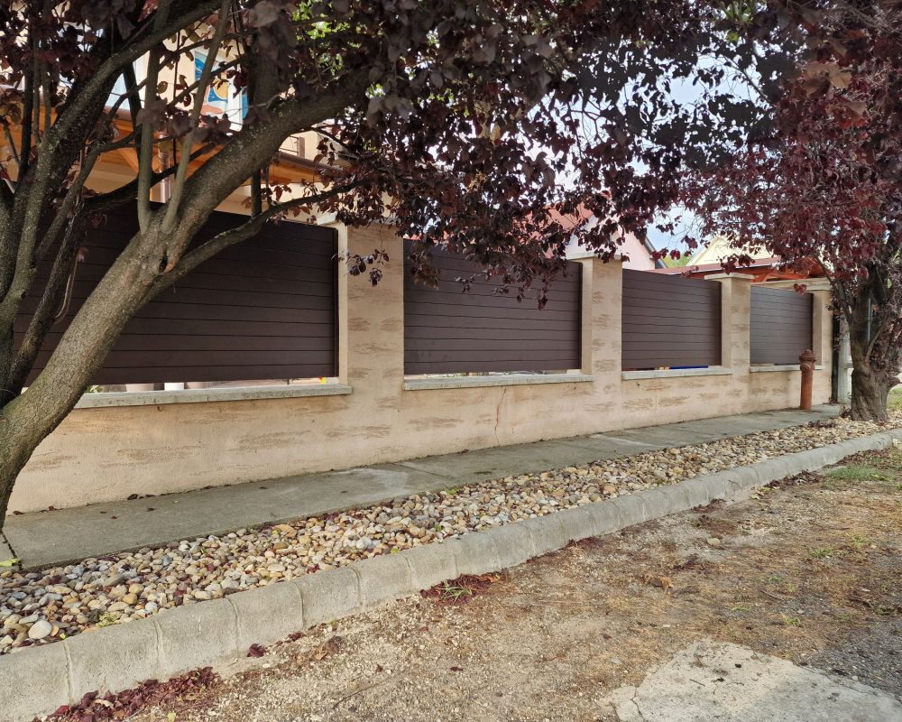 Zárt barna alumínium kerítés terméskővel fedett pillérekkel, utcafronti megoldás